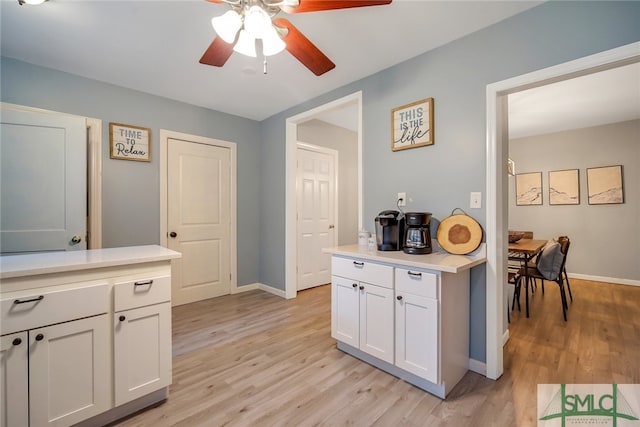 kitchen with white cabinets, ceiling fan, and light hardwood / wood-style flooring