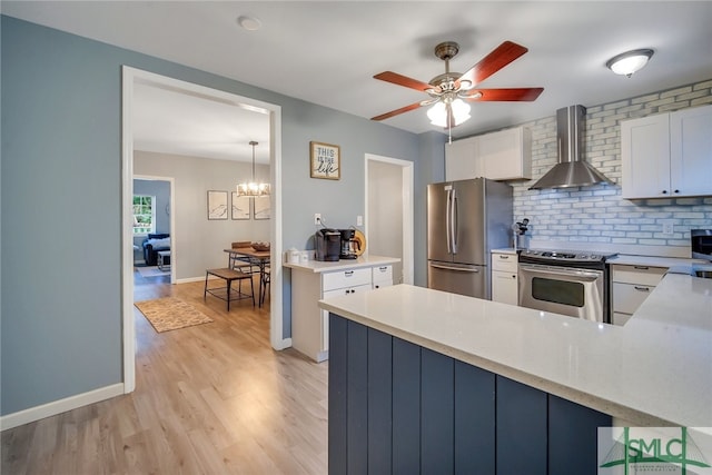 kitchen featuring kitchen peninsula, backsplash, stainless steel appliances, wall chimney range hood, and white cabinetry