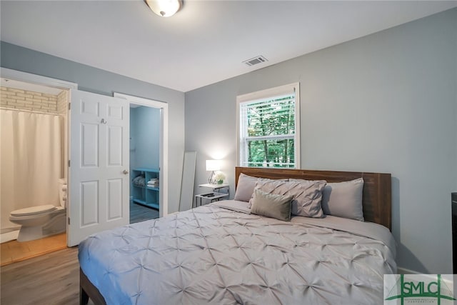 bedroom with connected bathroom and dark wood-type flooring