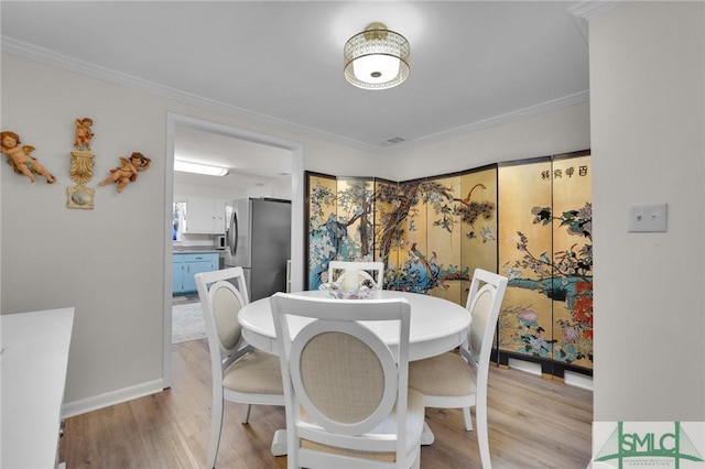 dining space with light wood-type flooring and ornamental molding