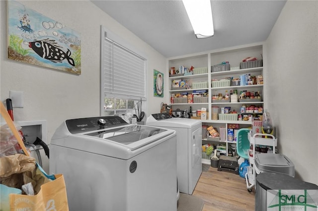 clothes washing area featuring washer and clothes dryer, light hardwood / wood-style floors, and a textured ceiling