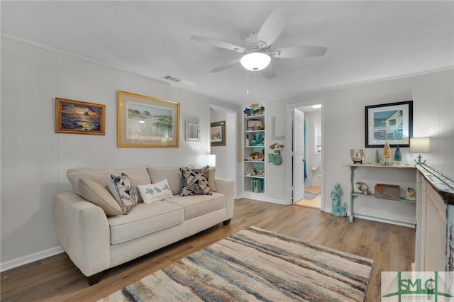 living room featuring hardwood / wood-style flooring, ceiling fan, built in features, and crown molding