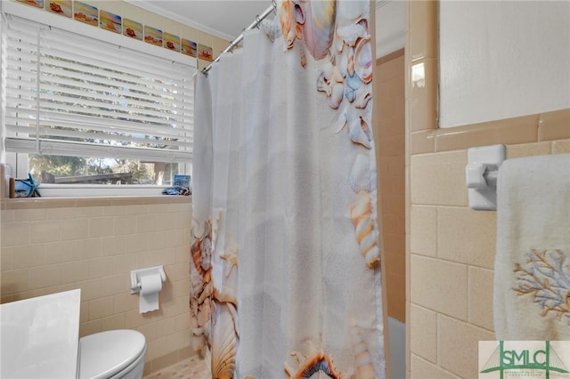 bathroom featuring toilet, shower / tub combo, tile walls, and ornamental molding