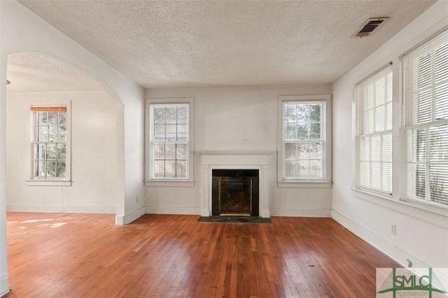 unfurnished living room featuring a textured ceiling and dark wood-type flooring