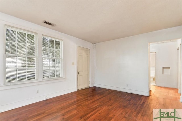 unfurnished room featuring a wealth of natural light and dark hardwood / wood-style flooring