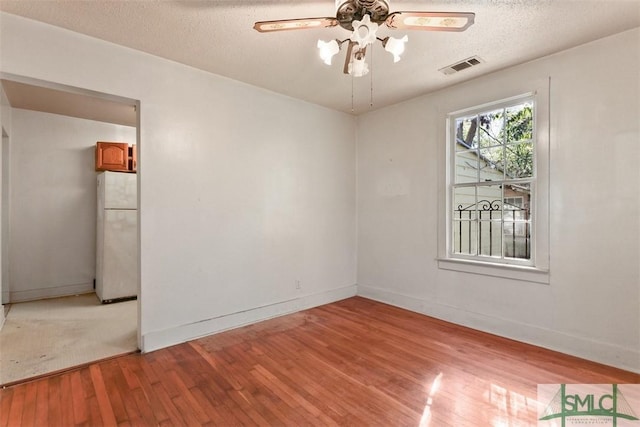 spare room with a textured ceiling, light hardwood / wood-style flooring, and ceiling fan