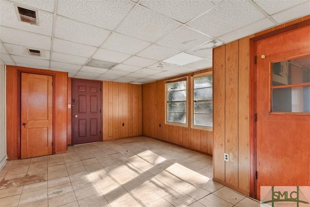 empty room with a drop ceiling and wooden walls