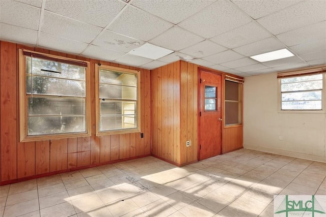 empty room with a paneled ceiling and wood walls