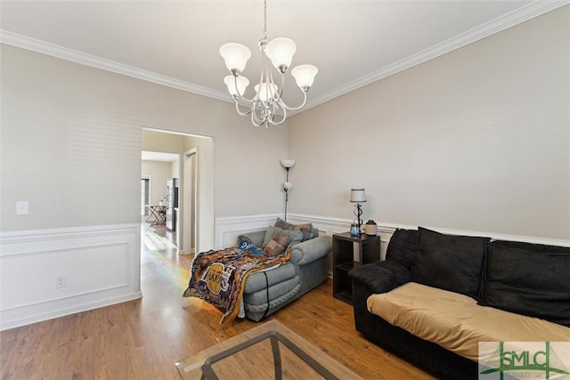 living room with hardwood / wood-style flooring, crown molding, and a notable chandelier