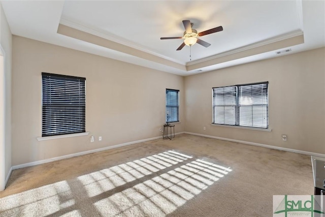 carpeted empty room featuring a tray ceiling, ceiling fan, and crown molding