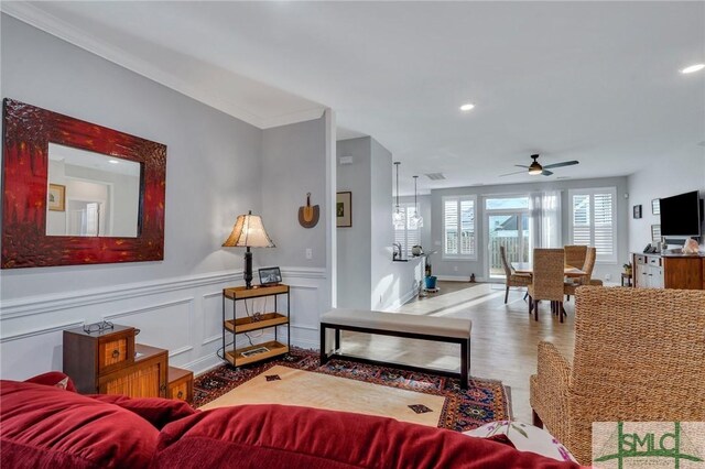 living room with hardwood / wood-style floors, ceiling fan, and crown molding