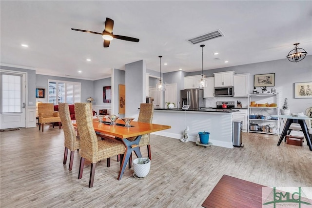 dining space featuring ceiling fan with notable chandelier and light hardwood / wood-style flooring