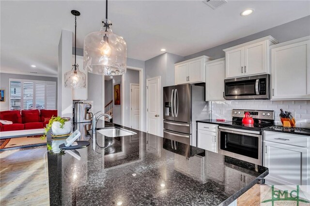 kitchen with white cabinetry, sink, hanging light fixtures, backsplash, and appliances with stainless steel finishes