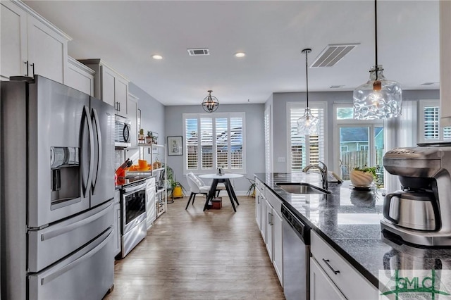 kitchen with white cabinets, pendant lighting, stainless steel appliances, and sink