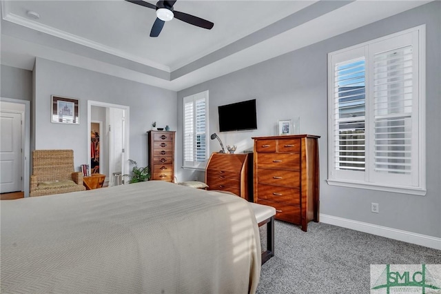 carpeted bedroom featuring multiple windows, a tray ceiling, and ceiling fan