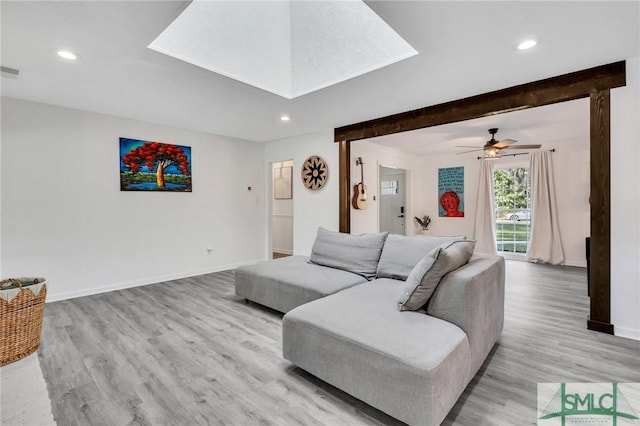 living room featuring ceiling fan, beam ceiling, and light wood-type flooring