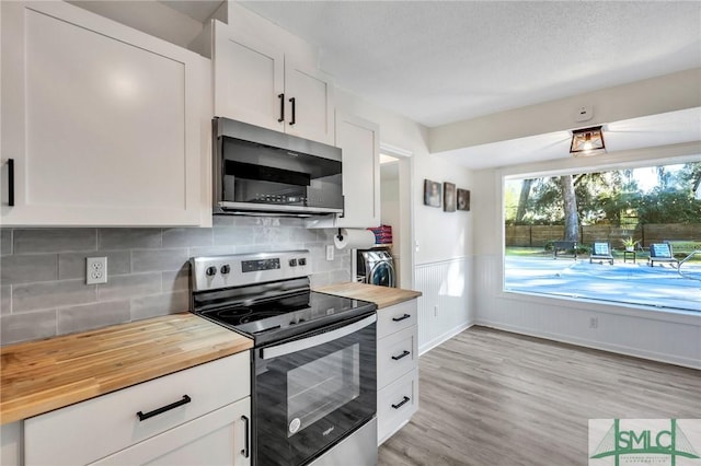 kitchen with butcher block countertops, white cabinetry, stainless steel appliances, and light wood-type flooring