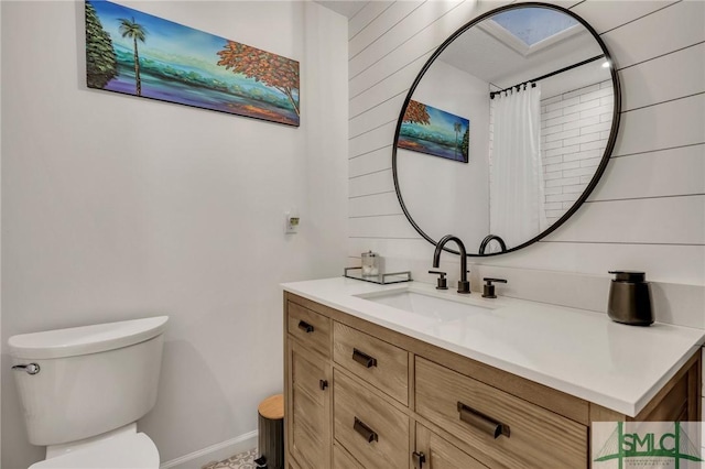 bathroom with a skylight, vanity, and toilet