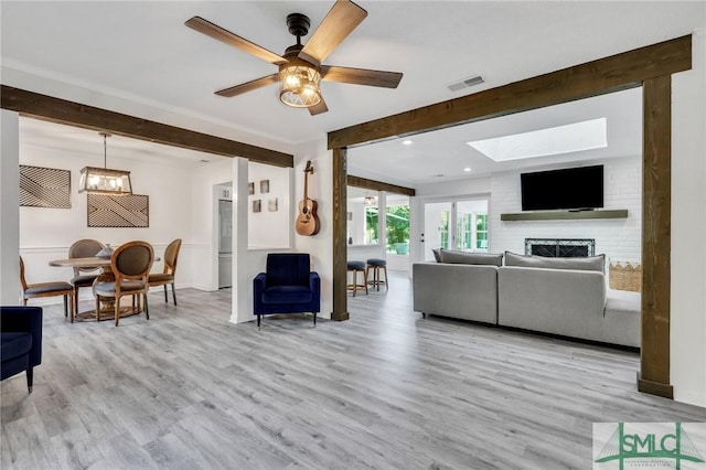 living room with ceiling fan, a large fireplace, and light hardwood / wood-style floors