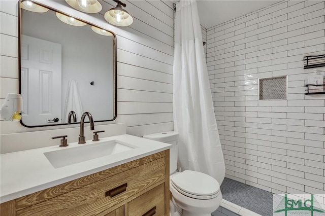 bathroom with a shower with curtain, toilet, vanity, and wooden walls