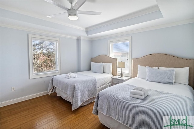 bedroom with a raised ceiling, multiple windows, and ceiling fan