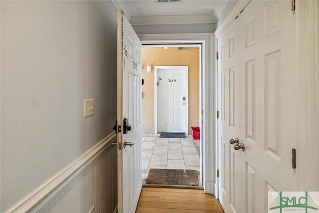 hallway featuring light wood-type flooring and ornamental molding