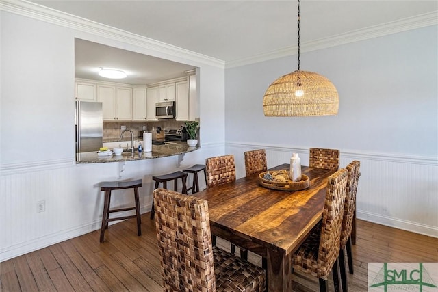 dining area with crown molding, sink, and dark hardwood / wood-style floors