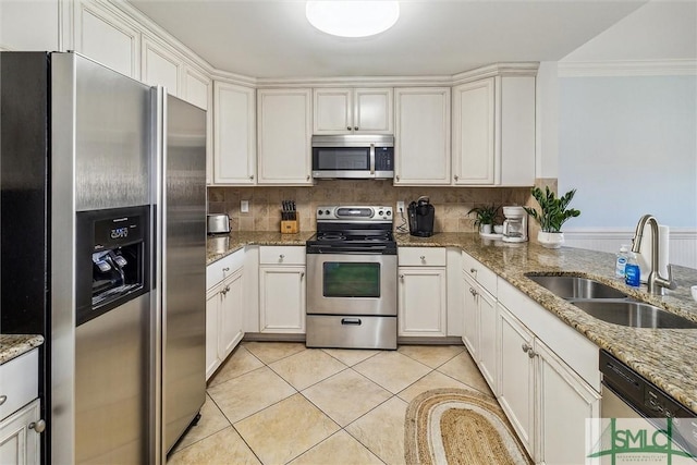 kitchen featuring light stone countertops, sink, light tile patterned flooring, white cabinets, and appliances with stainless steel finishes