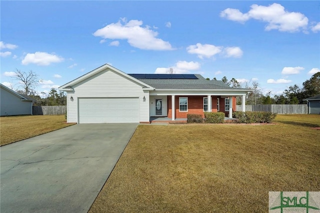 ranch-style home featuring a front yard, a garage, covered porch, and solar panels