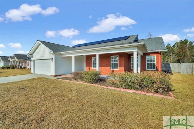 view of front of home with a porch, solar panels, a front yard, and a garage