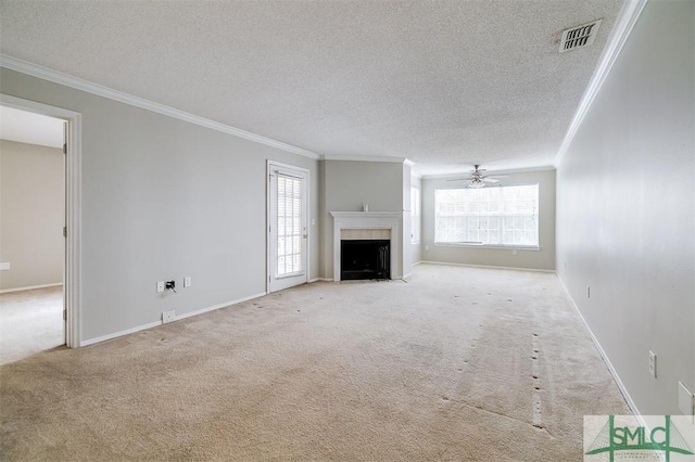 unfurnished living room with crown molding, ceiling fan, a textured ceiling, light colored carpet, and a tiled fireplace