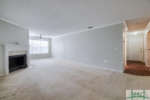 unfurnished living room featuring carpet flooring, ornamental molding, a textured ceiling, and a tile fireplace