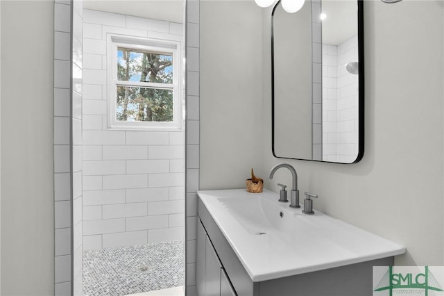 bathroom with a tile shower and vanity