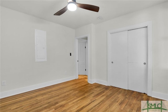 unfurnished bedroom featuring ceiling fan, light wood-type flooring, electric panel, and a closet