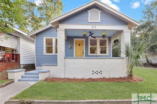 bungalow-style home with a front yard, a porch, and ceiling fan