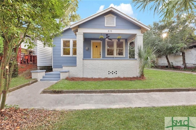 bungalow-style home with ceiling fan, covered porch, and a front yard