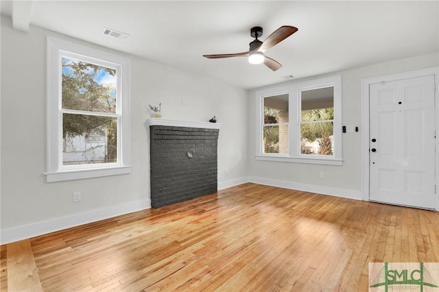 unfurnished living room with hardwood / wood-style floors, ceiling fan, and a fireplace