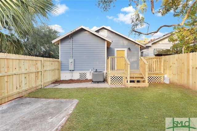 rear view of property with a lawn, cooling unit, and a deck