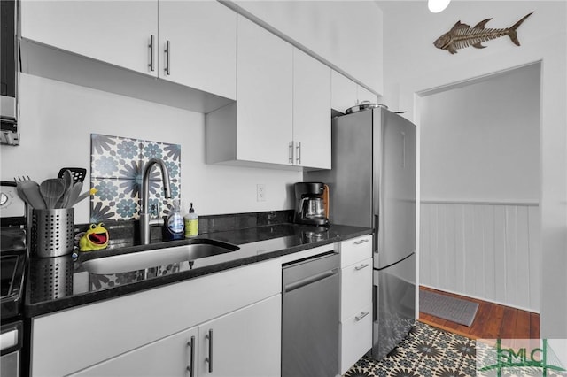 kitchen featuring white cabinetry, stainless steel appliances, sink, and dark stone counters