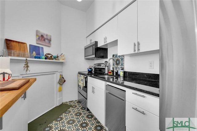 kitchen featuring white cabinetry, appliances with stainless steel finishes, sink, and dark stone countertops