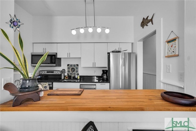 kitchen featuring appliances with stainless steel finishes, decorative light fixtures, and white cabinets