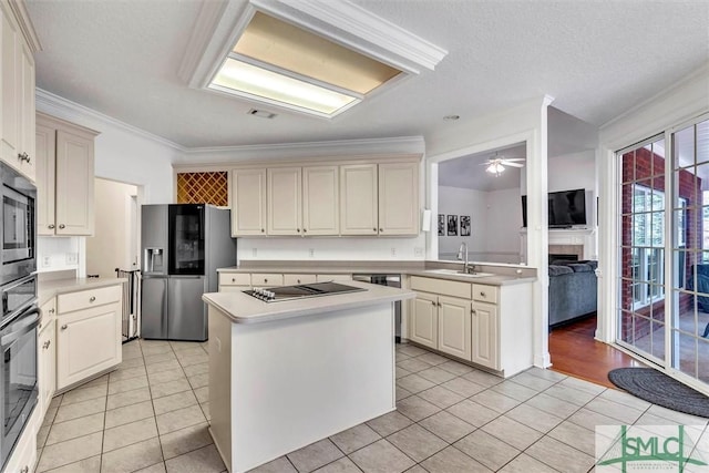 kitchen featuring ceiling fan, sink, a center island, light tile patterned floors, and appliances with stainless steel finishes