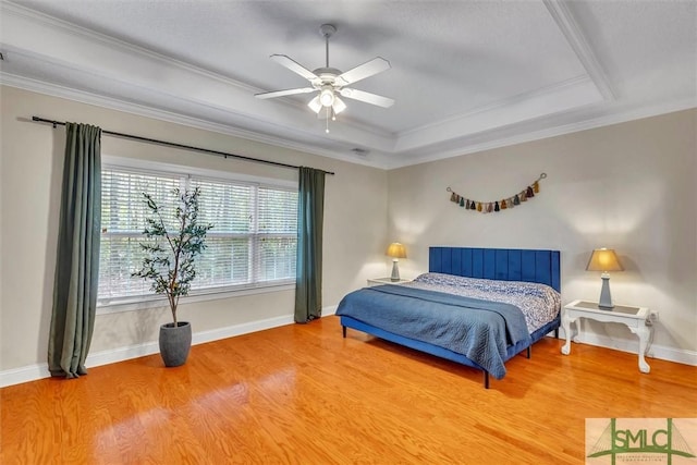 bedroom featuring wood-type flooring, a raised ceiling, ceiling fan, and crown molding