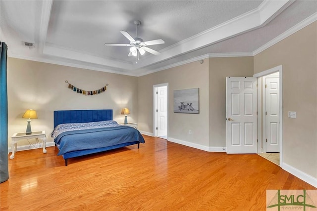 bedroom with wood-type flooring, a tray ceiling, ceiling fan, and crown molding