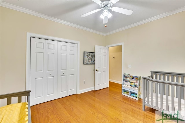 bedroom featuring a crib, a closet, ceiling fan, and ornamental molding