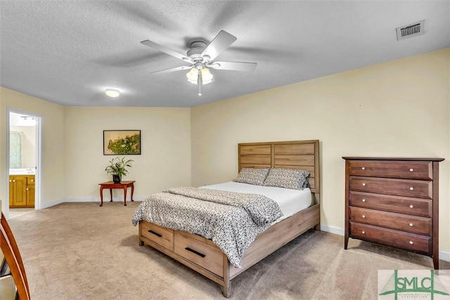 carpeted bedroom featuring a textured ceiling, ensuite bath, and ceiling fan