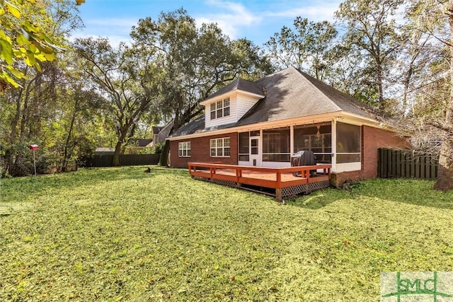 back of house featuring a lawn, a sunroom, and a wooden deck