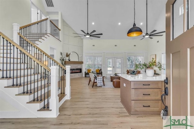 interior space featuring light hardwood / wood-style floors, french doors, light brown cabinetry, and a towering ceiling