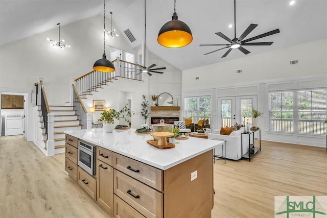 kitchen with stainless steel microwave, washer / clothes dryer, high vaulted ceiling, and pendant lighting