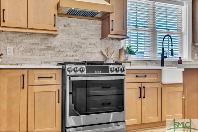 kitchen with stainless steel stove, backsplash, custom range hood, and light brown cabinets